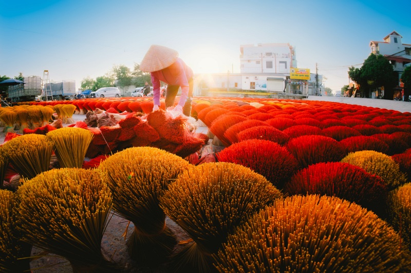 Vibrant crimson incense stick bouquets drying under the summer sun in Quang Phu Cau, Hanoi